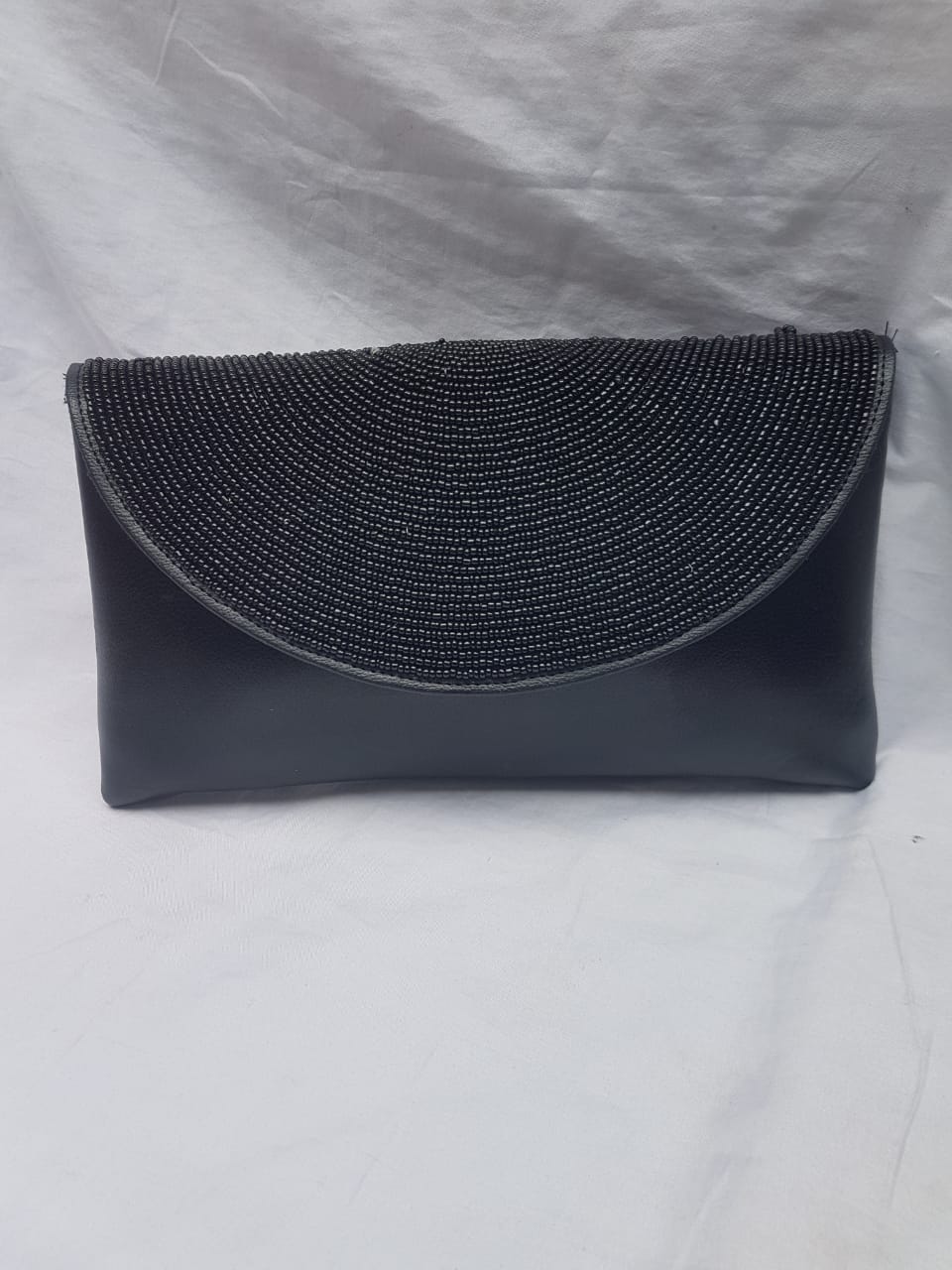 Black leather clutch purse decorated with black beads.