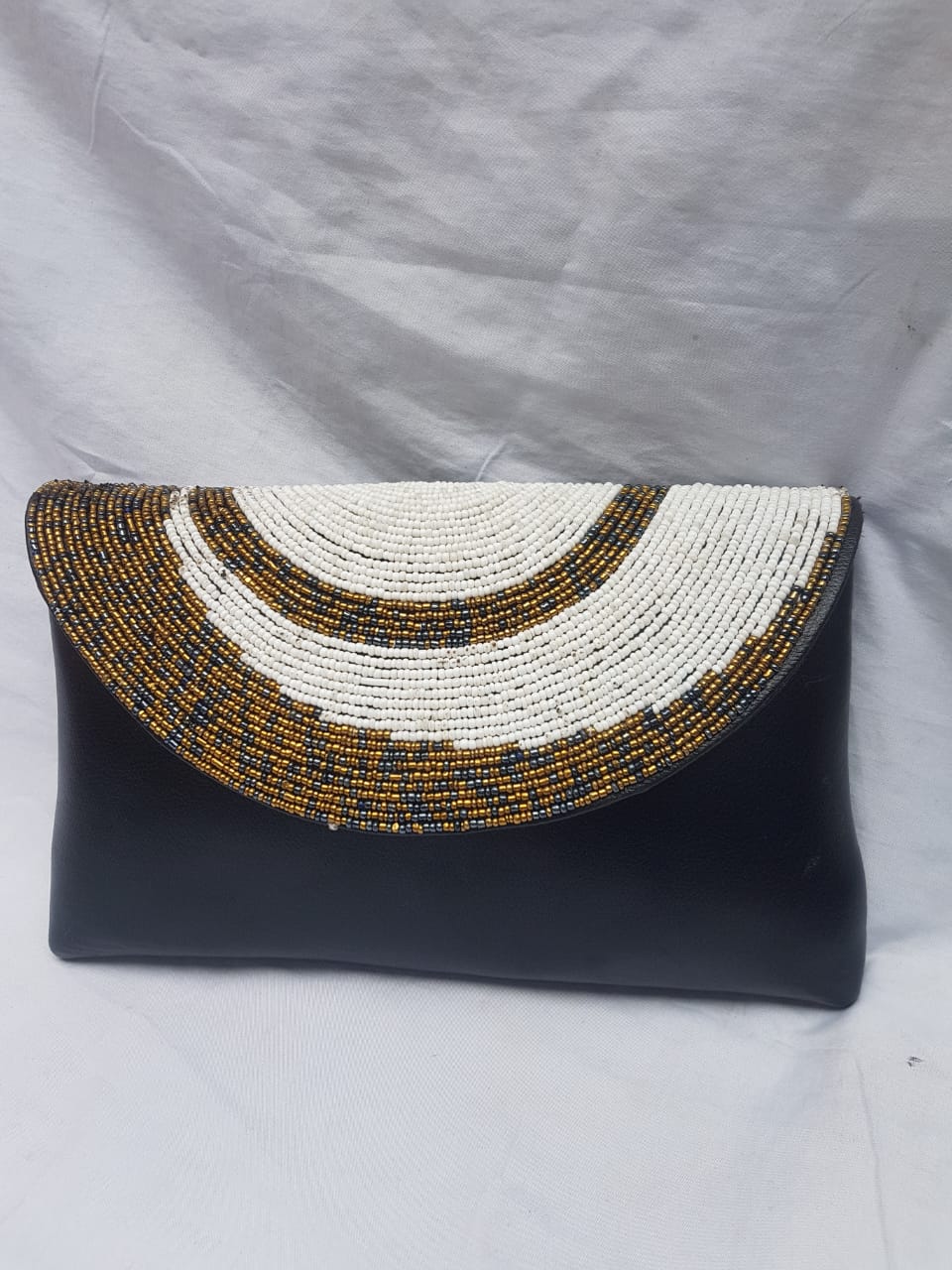 Black leather clutch purse decorated with white and brown beads.